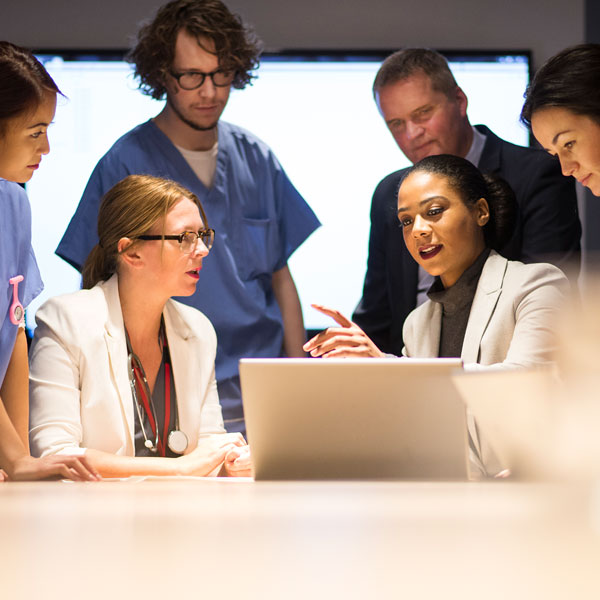 Group of physicians in discussion gathered around a laptop